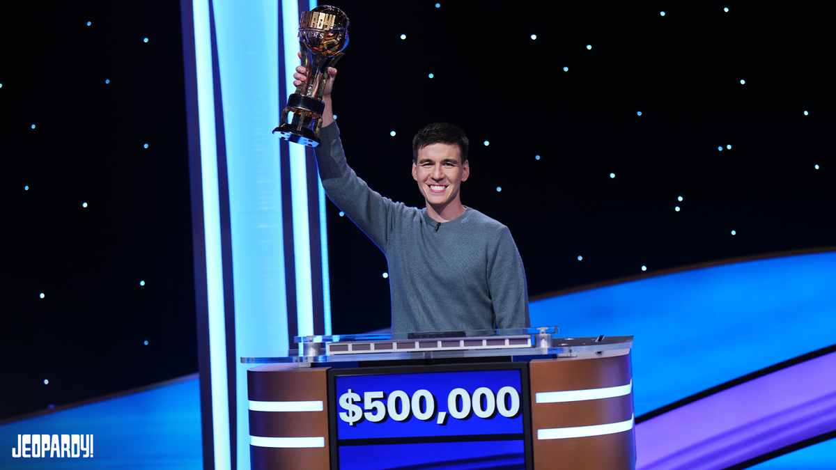 James Holzhauer holds the Trebek trophy with $500,000 grand prize on contestant podium