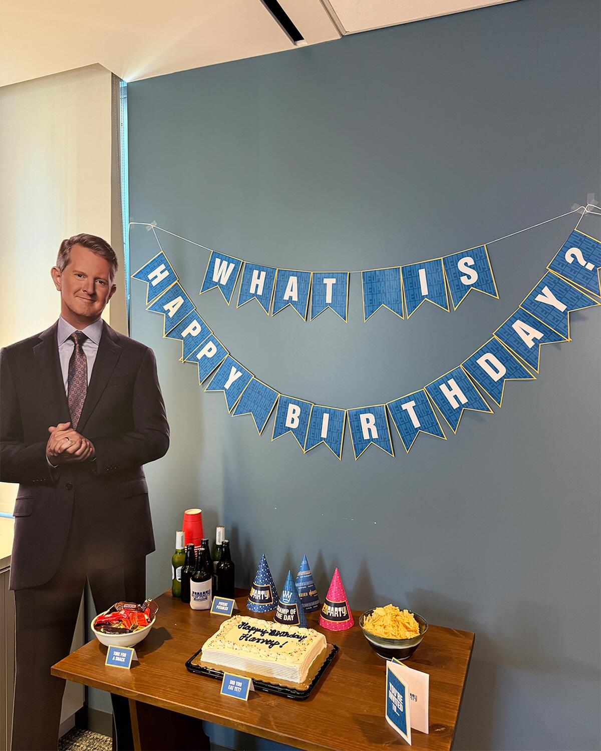 "What is Happy Birthday" Sign with a Cardboard cutout of Ken Jennings and party goodies. 