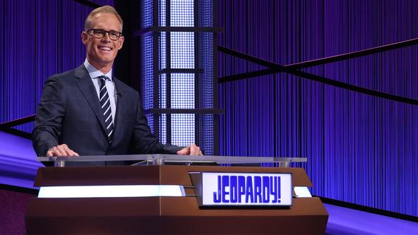 Joe Buck behind the Jeopardy! lectern.